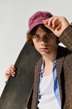 Yakışıklı genç, kendine güvenen bir şekilde kaykayla poz veriyor. Moda tarzını ve eşsiz yeteneğini sergiliyor..