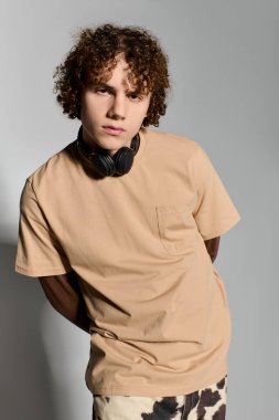 Kıvırcık saçlı yakışıklı genç, kulaklık takıp günlük kıyafetlerini giyerken hiç zorlanmadan poz veriyor..