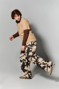 Kıvırcık saçlı yakışıklı genç, eşsiz moda kıyafetleri ve kulaklıklarıyla eğlenceli bir poz veriyor..