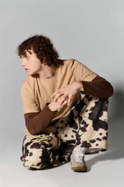 Yakışıklı genç, modern trendleri ve kişisel tarzını vurgulayarak şık kıyafetler içinde yaratıcı bir şekilde poz veriyor..