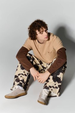 Yakışıklı genç, şık kıyafetler içinde yaratıcı bir şekilde poz veriyor, genç stili ve modern yeteneği somutlaştırıyor..