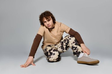 Kıvırcık saçlı genç adam kendine güvenen şık bir elbise giyiyor..