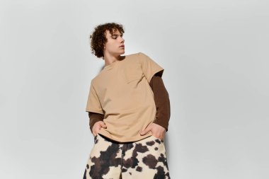 Yakışıklı genç gururla şık bir tişört ve desenli pantolonu olan modaya uygun bir kıyafet sergiliyor..