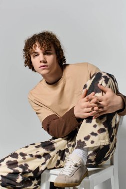 Genç, bireyselliği ve güveni ifade ederek, rahat bir şekilde otururken modern tarzı sergiliyor.