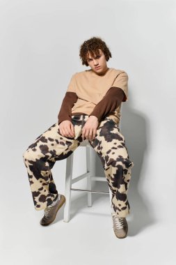 Yakışıklı genç, modern moda tercihlerini vurgulayarak, modaya uygun bir kıyafetin içinde güven içinde poz veriyor..