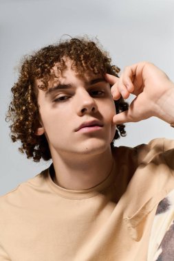 Yakışıklı genç düşünceli bir şekilde poz veriyor, şık görünüşünü ve eşsiz kıvırcık saç stilini vurguluyor..