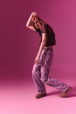 Neşeli bir insan, canlı pembe bir arka plana karşı şık bir elbise modeller..