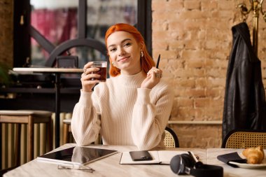 Mutluluk dolu genç bir kadın, sıcak bir kafe atmosferiyle çevrili, gülümseyerek bir içki tutuyor..