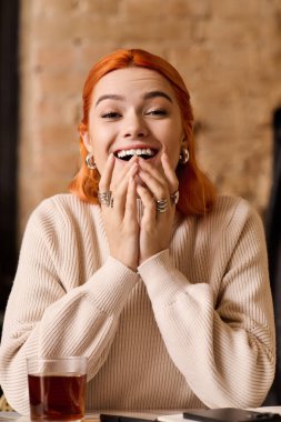 Canlı kızıl saçlı genç bir kadın modern bir kafede ışıl ışıl gülümsüyor ve eğleniyor..