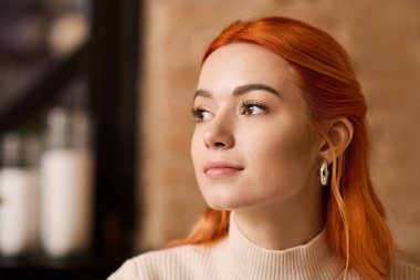 Kızıl saçlı güzel bir kadın şık bir kafede dinleniyor, düşüncelere dalmış..