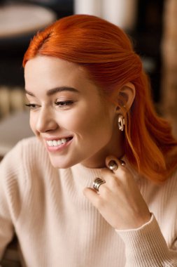 Neşeli, kızıl saçlı genç bir kadın şık bir kafede rahatlar ve zamanının tadını çıkarır..