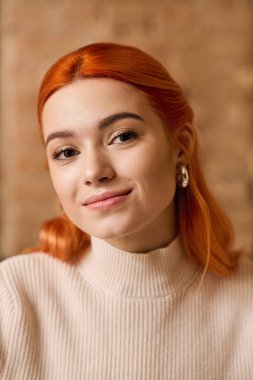 Kızıl saçlı güzel bir kadın modern bir kafede rahatlıyor, sıcaklık ve tarz saçıyor..