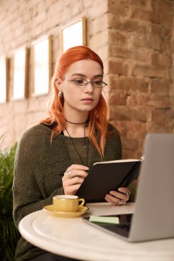 Kızıl saçlı güzel bir kadın modern bir kafede oturuyor..