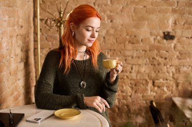 Gündelik giysiler içinde güzel bir kadın içkisini yudumluyor, modern bir kafede dinleniyor..