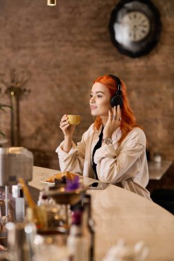 Şık bir kafede dinlenirken çarpıcı kızıl saçlı genç bir kadın kahvesini yudumluyor..