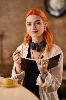 Canlı kızıl saçlı genç bir kadın bir kafede not alır ve bir ilham anını kucaklar..