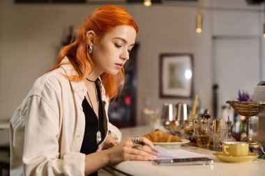 Samimi bir kafede, kızıl saçlı genç bir kadın defterine şöyle yazıyor, etrafı enfes hediyelerle çevrili..