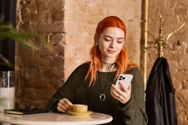 Kızıl saçlı genç bir kadın kafede kahve ve tomarlardan hoşlanır.