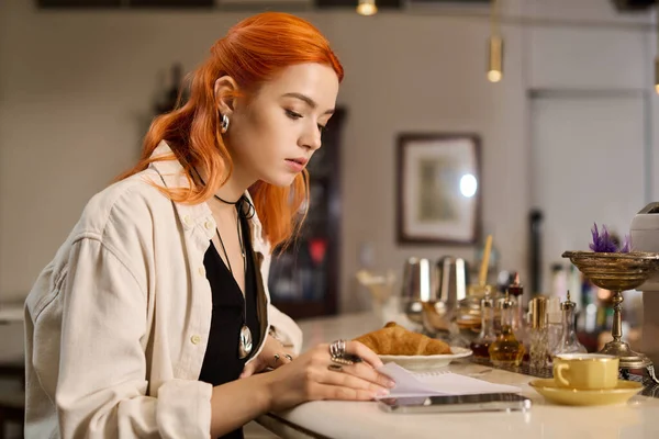 Samimi bir kafede, kızıl saçlı genç bir kadın defterine şöyle yazıyor, etrafı enfes hediyelerle çevrili..