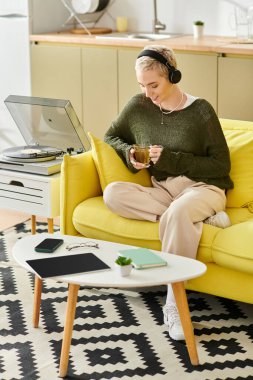 Genç bir kadının sarı bir koltukta dinlenip çayını yudumlaması gibi parlak ve davetkar bir atmosfer..