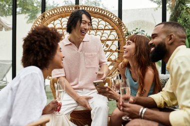 Genç arkadaşlar, açık hava kafeteryasında içkilerini yudumlarken kahkahalarını paylaşıyorlar..