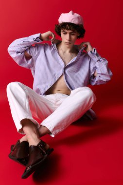 Şık genç adam kendine güvenerek poz veriyor, şık bir kıyafet ve neşeli bir hava sergiliyor..