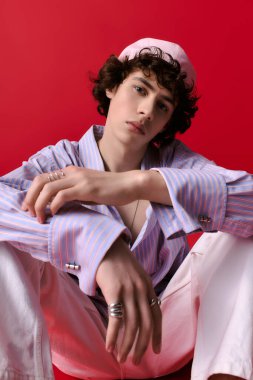 Genç ve modaya uygun bir adam, eşsiz stili ve karizmasını sergileyerek rahatça oturur..