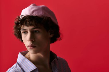 Pembe şapkalı ve rahat gömlekli yakışıklı genç adam şık bir ortamda düşünceli bir şekilde bakıyor..