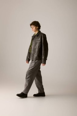 Şık bir genç adam zarif bir zemin üzerinde yürüyor, modern moda sergiliyor..