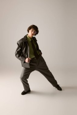 Genç bir adam modern bir kıyafetle şık bir şekilde poz veriyor. İçeriye cazibe ve güven yayıyor..