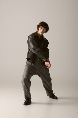 Kendine güvenen genç adam, sanatsal bir duruşta pürüzsüz bir arkaplan karşısında eşsiz bir tarz sergiliyor..