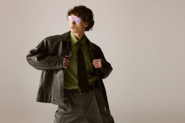 Genç, yakışıklı bir adam şık bir ceketi ve eşsiz gözlükleriyle kendine güvenen bir şekilde poz verir..