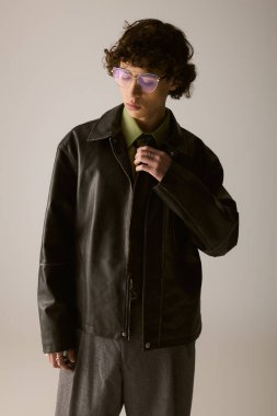 Şık giyinmiş genç bir adam rahat duruyor, moda yeteneğini sergiliyor..