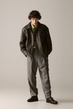 Şık bir stüdyodaki kendine güvenen genç adam modaya uygun, çağdaş bir kıyafet giyiyor..