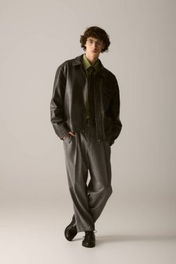 Genç ve yakışıklı bir adam kendine güvenerek modern stili, şık bir elbise ve rahat bir pozla ifade ediyor..