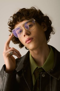 Genç bir adam modaya uygun kıyafetlerini ve şık gözlüklerini sergiliyor, eşsiz moda anlayışını sergiliyor..