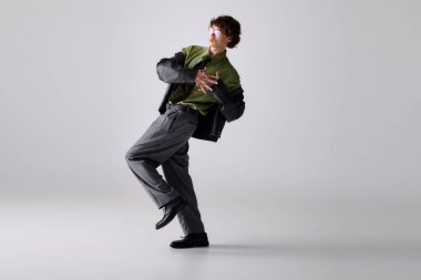 Şık giyinmiş genç bir adam stüdyoda kendine güvenen, eşsiz bir poz verir..