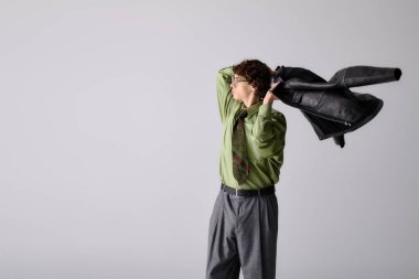 Şık giyinmiş kendine güvenen genç bir adam stüdyoda poz verirken siyah bir ceket giyiyor..