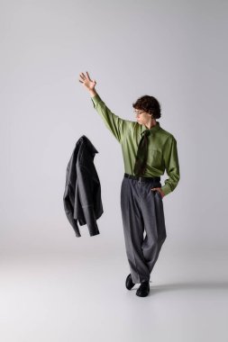 Modern bir stüdyoda, kendine has tarzını sergileyen, ceketli, modaya uygun genç adam jestleri..