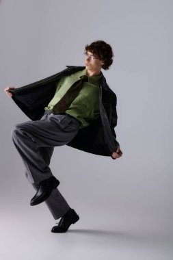 Yakışıklı genç adam kendine güveni olan şık bir elbise içinde poz veriyor. Stüdyo ışığı altında tarz ve cazibe yayıyor..