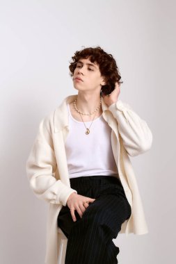 Yakışıklı genç adam basit bir arkaplana karşı şık bir elbise içinde düşünceli bir şekilde poz verir..