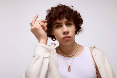 Yakışıklı genç adam zarif poz veriyor, şık aksesuarlarını ve şık kıyafetlerini vurguluyor..