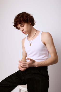 Yakışıklı bir genç adam rahat bir tavırla düşünürken moda anlayışını sergiliyor..