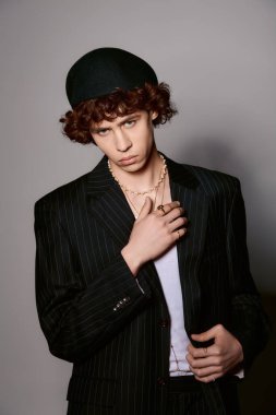 Modayı takip eden genç bir adam zarif bir takım elbise ve kalın aksesuarlarla benzersiz tarzını sergiliyor..