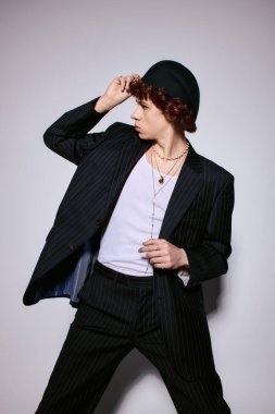 Yakışıklı genç, arka planda dinamik bir duruş sergilerken moda tarzını sergiliyor.