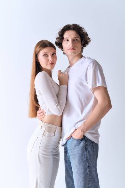 Neşeli çift birlikte poz veriyor, aşklarını ve tarzlarını modern, gri bir stüdyoda sergiliyorlar..