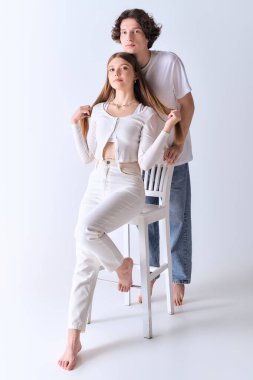 Mutlu çift şık gri bir stüdyoda birlikte poz veriyor, sevgi ve bağ yayıyorlar..