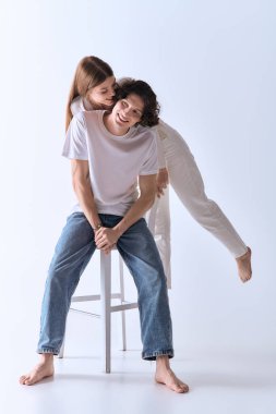 Mutlu genç çift gri bir stüdyoda samimi pozlar veriyor. Birbirlerine sevgi ve sıcaklık saçıyorlar..