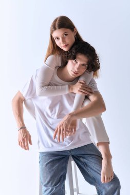 Genç çift aşklarını ve neşelerini ifade ederken şık, gri bir ortamda birlikte poz veriyorlar..