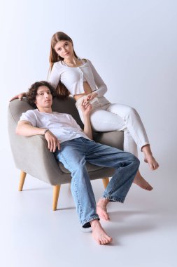 Neşeli bir çift şık, gri bir stüdyoda birlikte poz verir, aşk ve mutluluk saçar..